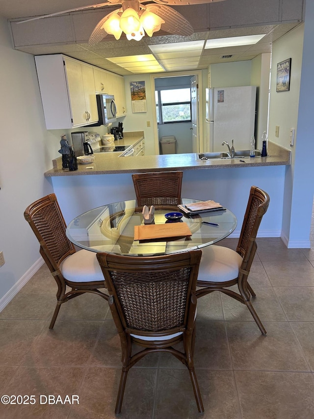 dining room featuring a paneled ceiling, tile patterned floors, and baseboards