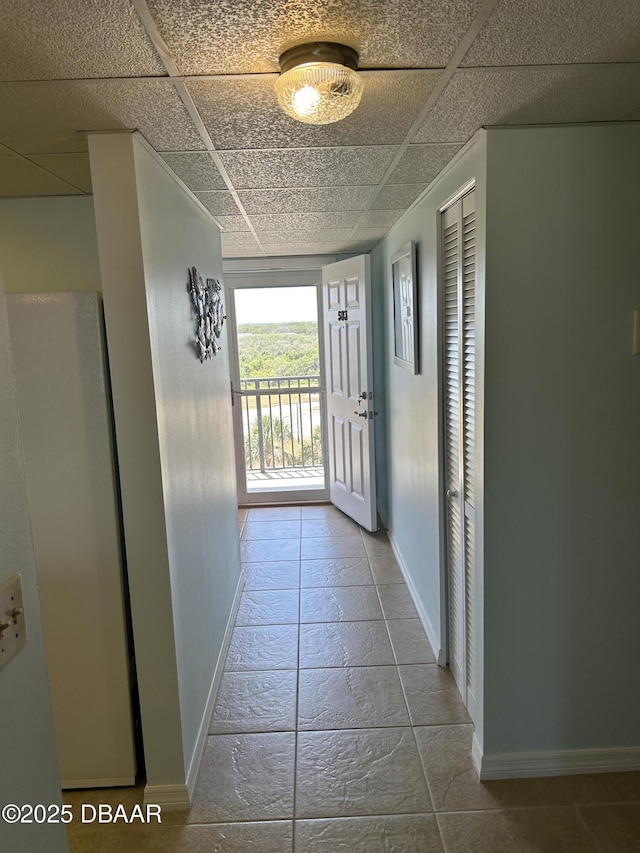 hall featuring baseboards and a drop ceiling