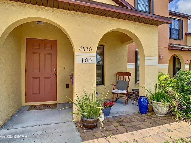 entrance to property with covered porch and stucco siding