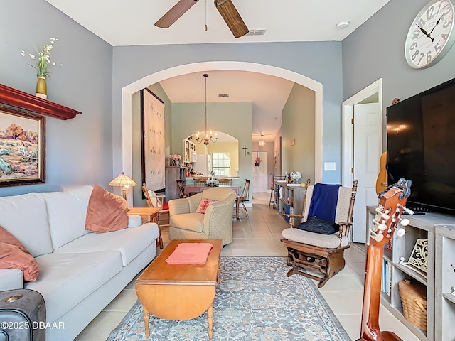 living area featuring arched walkways, visible vents, light tile patterned flooring, and ceiling fan with notable chandelier