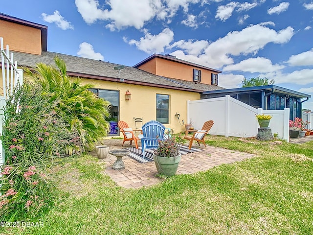back of house featuring a patio, a sunroom, stucco siding, fence, and a lawn