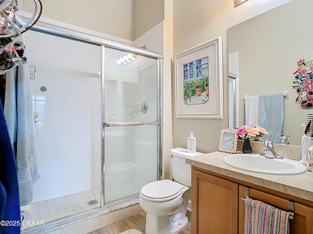 bathroom with a stall shower, vanity, toilet, and wood finished floors