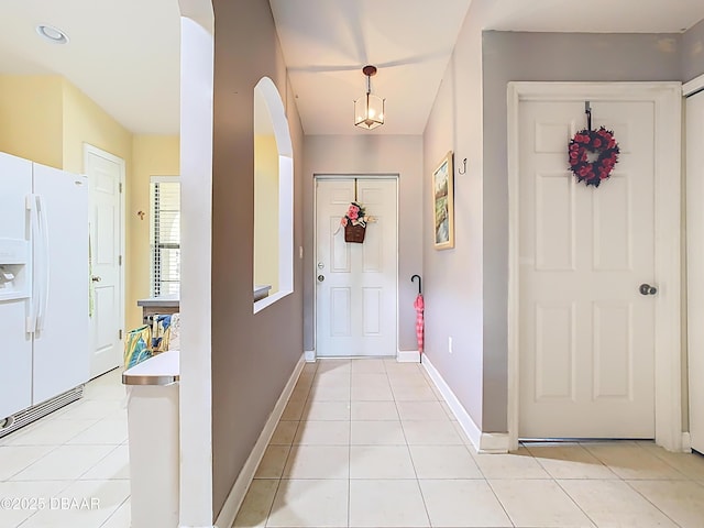 entrance foyer with light tile patterned floors, baseboards, and arched walkways