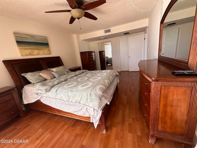 bedroom featuring ceiling fan, hardwood / wood-style floors, and a textured ceiling