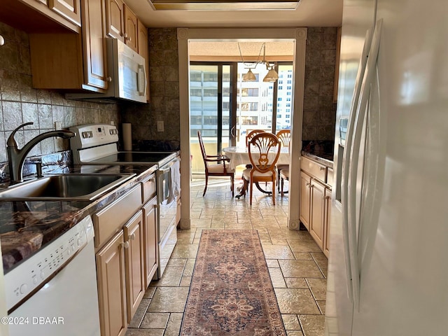 kitchen featuring white appliances, backsplash, sink, dark stone countertops, and decorative light fixtures