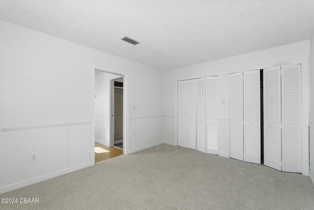 unfurnished bedroom with light colored carpet and a textured ceiling