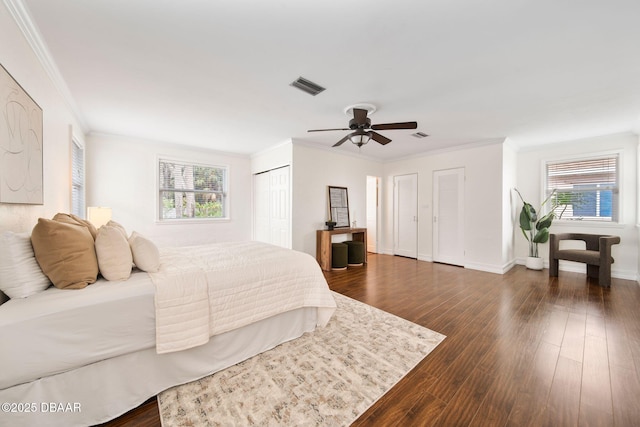 bedroom featuring multiple closets, ornamental molding, and dark hardwood / wood-style floors