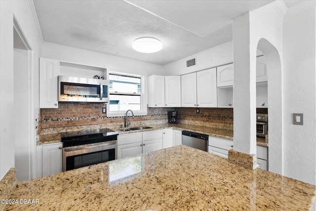 kitchen featuring white cabinetry, sink, stainless steel appliances, light stone counters, and decorative backsplash