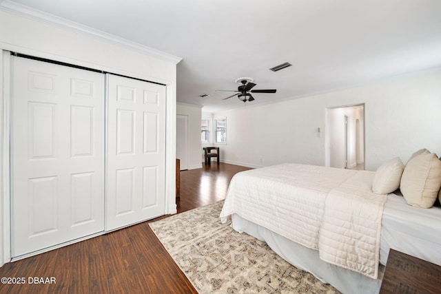 bedroom with crown molding, dark wood-type flooring, and a closet