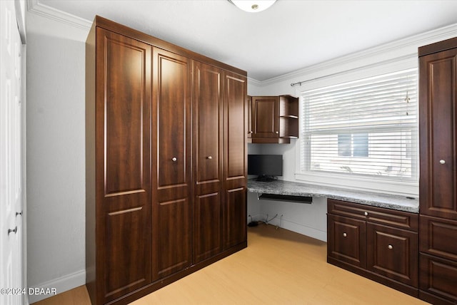 office area with ornamental molding, built in desk, and light wood-type flooring