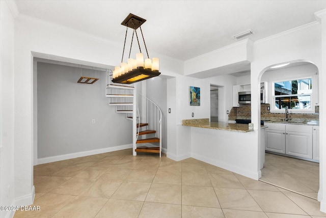 kitchen featuring tasteful backsplash, white cabinetry, ornamental molding, and light stone counters