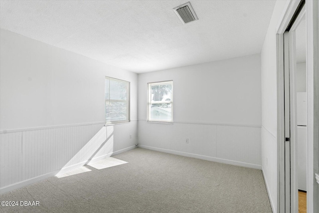 unfurnished room featuring light carpet and a textured ceiling