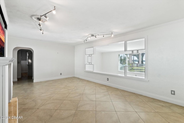 tiled spare room featuring track lighting and ornamental molding