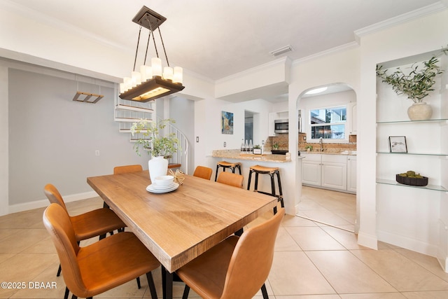 dining room featuring crown molding, sink, light tile patterned floors, and an inviting chandelier