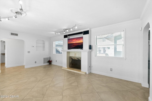 unfurnished living room featuring a high end fireplace, light tile patterned floors, crown molding, and a healthy amount of sunlight