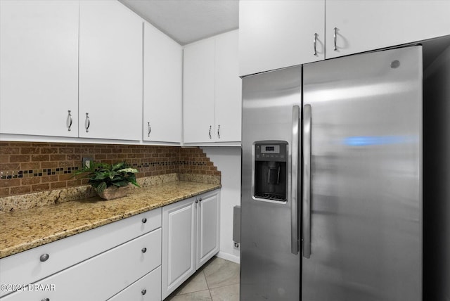 kitchen with light stone countertops, tasteful backsplash, white cabinets, stainless steel fridge with ice dispenser, and light tile patterned flooring