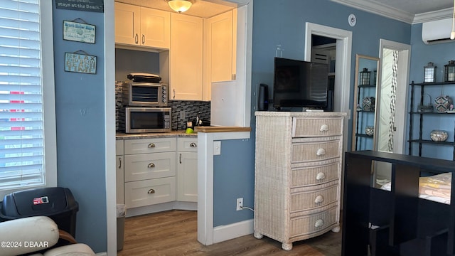 kitchen with a wall mounted AC, white cabinetry, dark hardwood / wood-style flooring, and ornamental molding