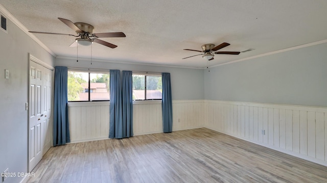 8 Fox Run Trl, Ormond Beach, FL 32174 - empty room featuring a ceiling fan, wood finished floors, ornamental molding, a wainscoted wall, and a textured ceiling