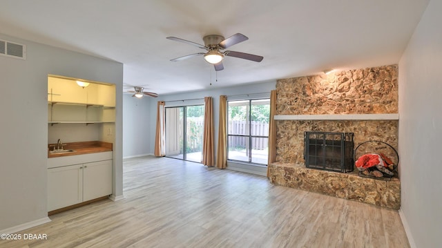 8 Fox Run Trl, Ormond Beach, FL 32174 - unfurnished living room with light wood-style floors, a stone fireplace, and ceiling fan