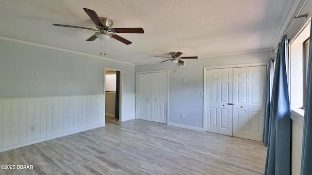 8 Fox Run Trl, Ormond Beach, FL 32174 - unfurnished bedroom with two closets, light wood-style floors, a textured ceiling, crown molding, and wainscoting