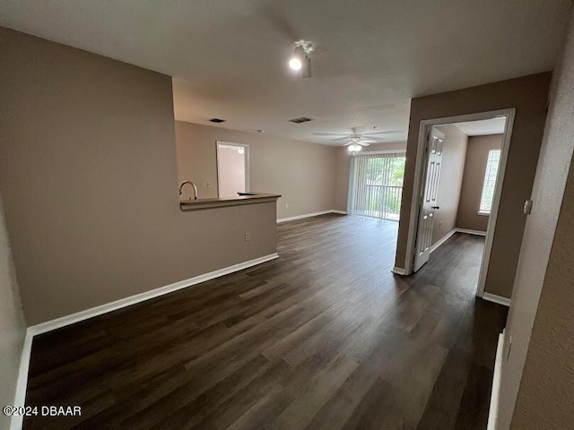 unfurnished living room with dark wood-type flooring and ceiling fan