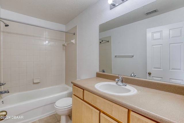 full bathroom featuring tiled shower / bath, a textured ceiling, vanity, tile patterned floors, and toilet