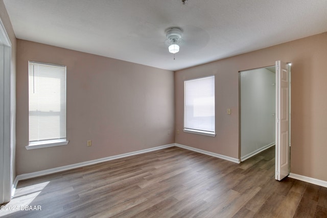 unfurnished bedroom with ceiling fan, wood-type flooring, multiple windows, and a textured ceiling