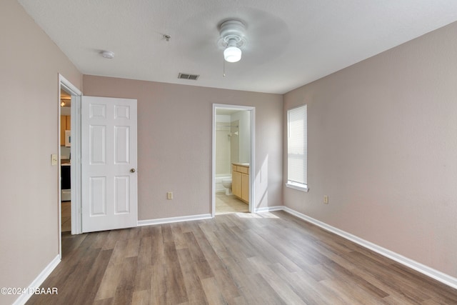 unfurnished bedroom with a closet, a spacious closet, ceiling fan, and light hardwood / wood-style flooring