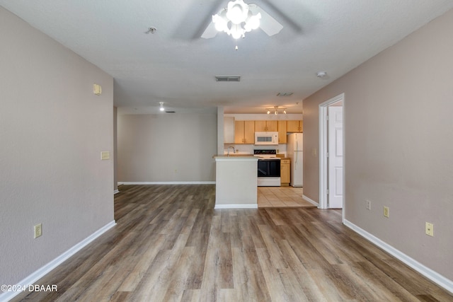 unfurnished living room with ceiling fan, sink, and light hardwood / wood-style flooring