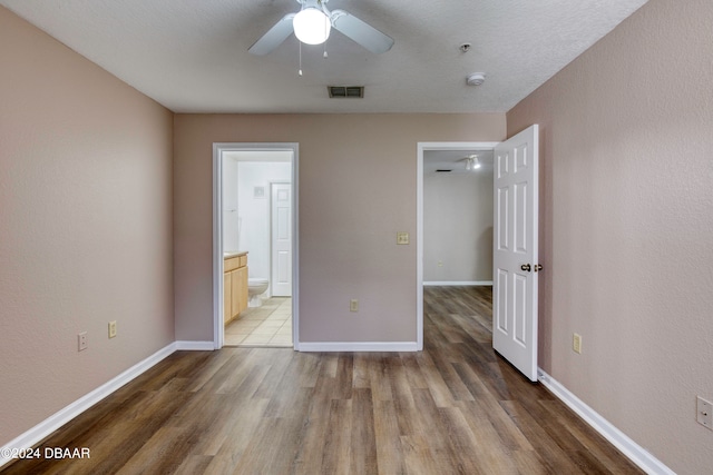 unfurnished bedroom featuring a textured ceiling, wood-type flooring, ceiling fan, and ensuite bath