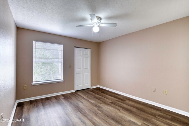 unfurnished bedroom featuring a textured ceiling, dark hardwood / wood-style floors, ceiling fan, and a closet