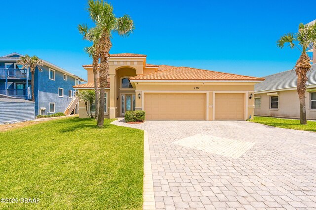 4427 S Atlantic Ave, Ponce Inlet, FL 32127 - mediterranean / spanish-style home featuring an attached garage, decorative driveway, a front yard, stucco siding, and a tiled roof