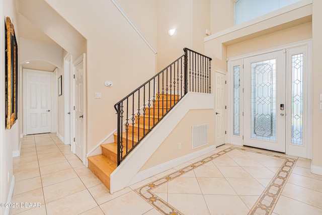 4427 S Atlantic Ave, Ponce Inlet, FL 32127 - entryway featuring baseboards, stairs, arched walkways, tile patterned flooring, and a towering ceiling
