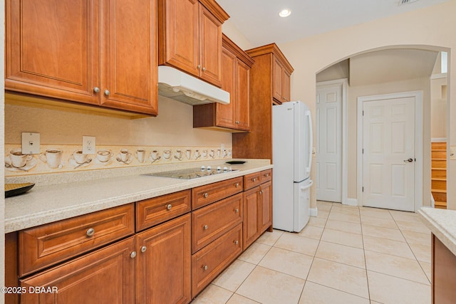 4427 S Atlantic Ave, Ponce Inlet, FL 32127 - kitchen featuring freestanding refrigerator, under cabinet range hood, electric stovetop, light tile patterned flooring, and light countertops
