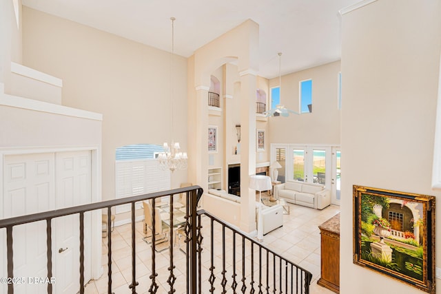 4427 S Atlantic Ave, Ponce Inlet, FL 32127 - stairs featuring a high ceiling, a chandelier, tile patterned floors, plenty of natural light, and arched walkways