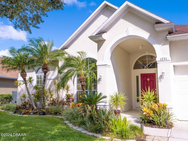 view of exterior entry featuring a garage and a yard