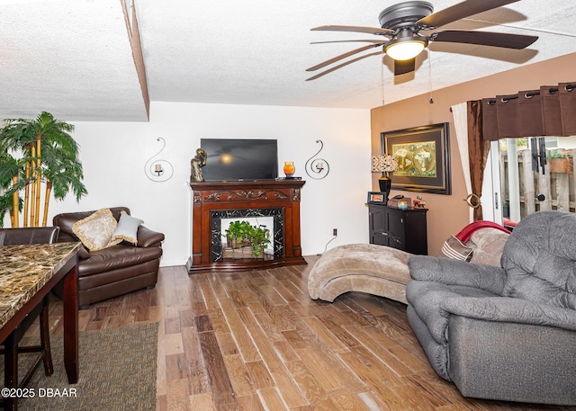 living room with hardwood / wood-style floors, a fireplace, a textured ceiling, and ceiling fan