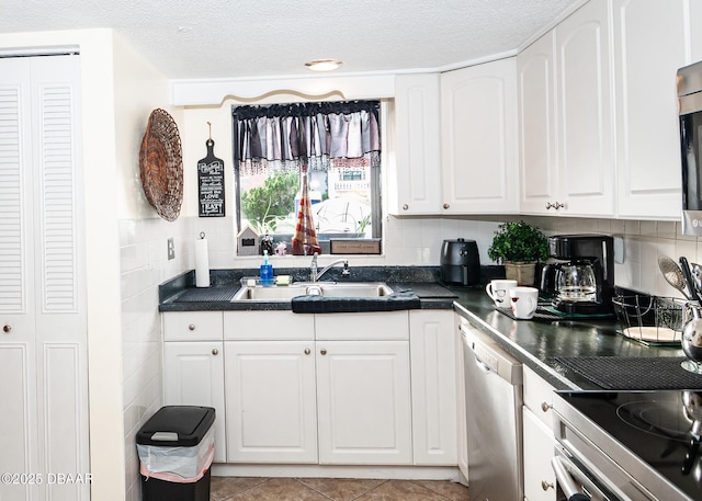 kitchen with white cabinetry, sink, light tile patterned floors, stainless steel appliances, and a textured ceiling