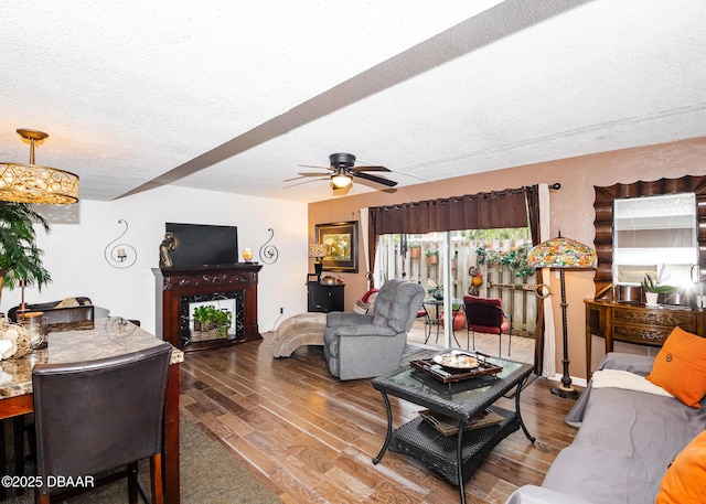 living room with ceiling fan, wood-type flooring, and a textured ceiling