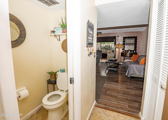 bathroom with tile patterned flooring, a textured ceiling, and toilet