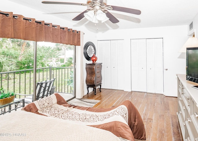 bedroom with ceiling fan, two closets, light hardwood / wood-style flooring, and access to outside