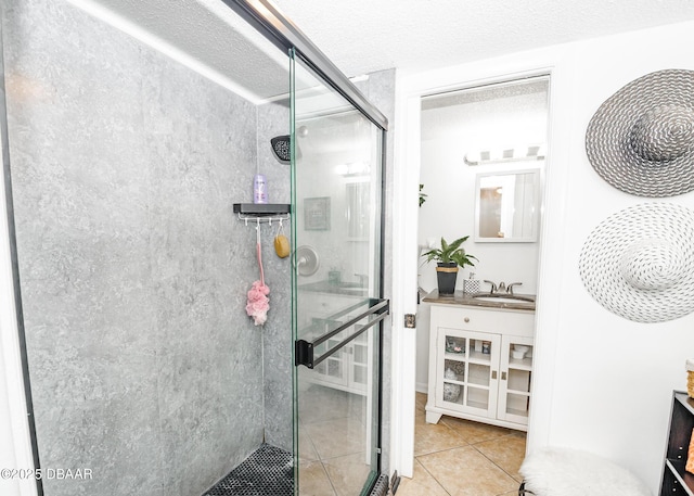 bathroom featuring tile patterned flooring, vanity, a shower with door, and a textured ceiling