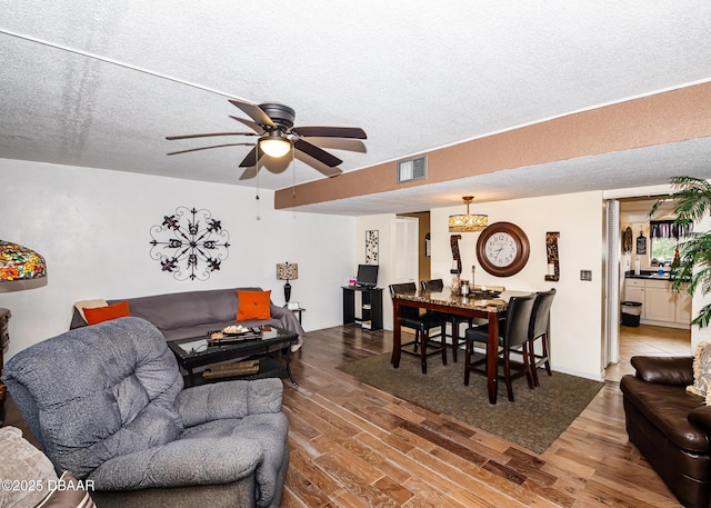 living room featuring ceiling fan, wood-type flooring, and a textured ceiling