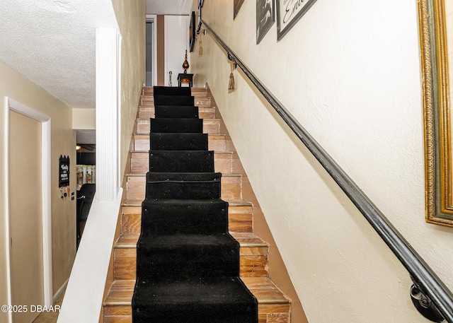 stairs featuring a textured ceiling