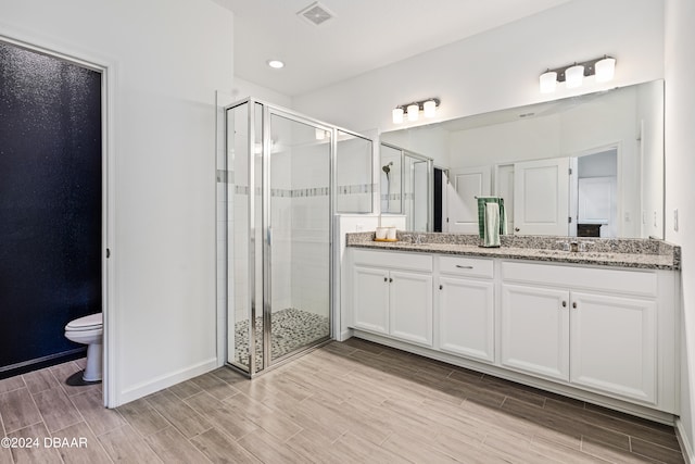 bathroom with an enclosed shower, vanity, and toilet