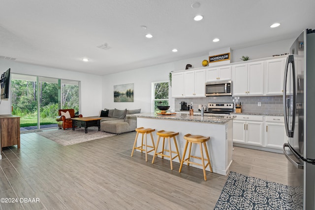 kitchen featuring white cabinets, a kitchen island with sink, light hardwood / wood-style floors, and stainless steel appliances