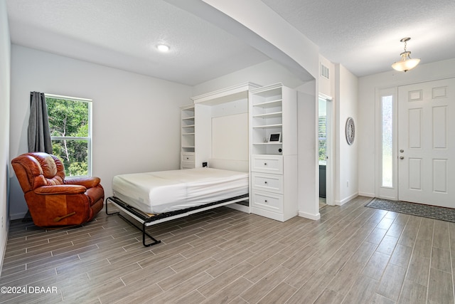 bedroom with hardwood / wood-style flooring, multiple windows, and a textured ceiling