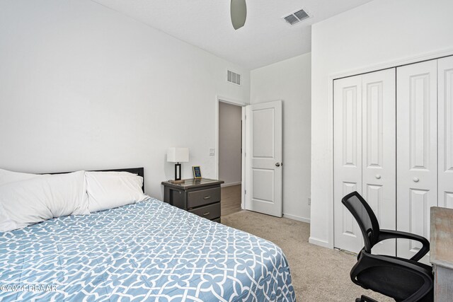 bedroom with ceiling fan, light carpet, and a closet