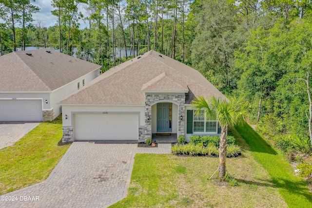 view of front facade with a garage, a water view, and a front lawn