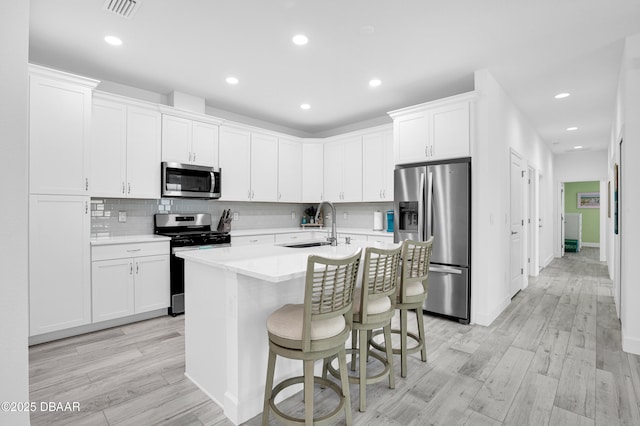 802 Margaritaville Ave, Daytona Beach, FL 32124 - kitchen featuring appliances with stainless steel finishes, a sink, light wood finished floors, light countertops, and a kitchen island with sink
